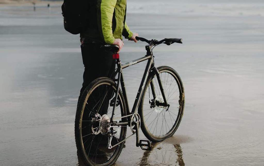 amok retrospec black bicycle on a beach